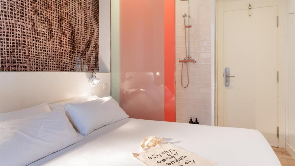 a bedroom with a white bed and a shower at chic&basic Tallers Hostal in Barcelona