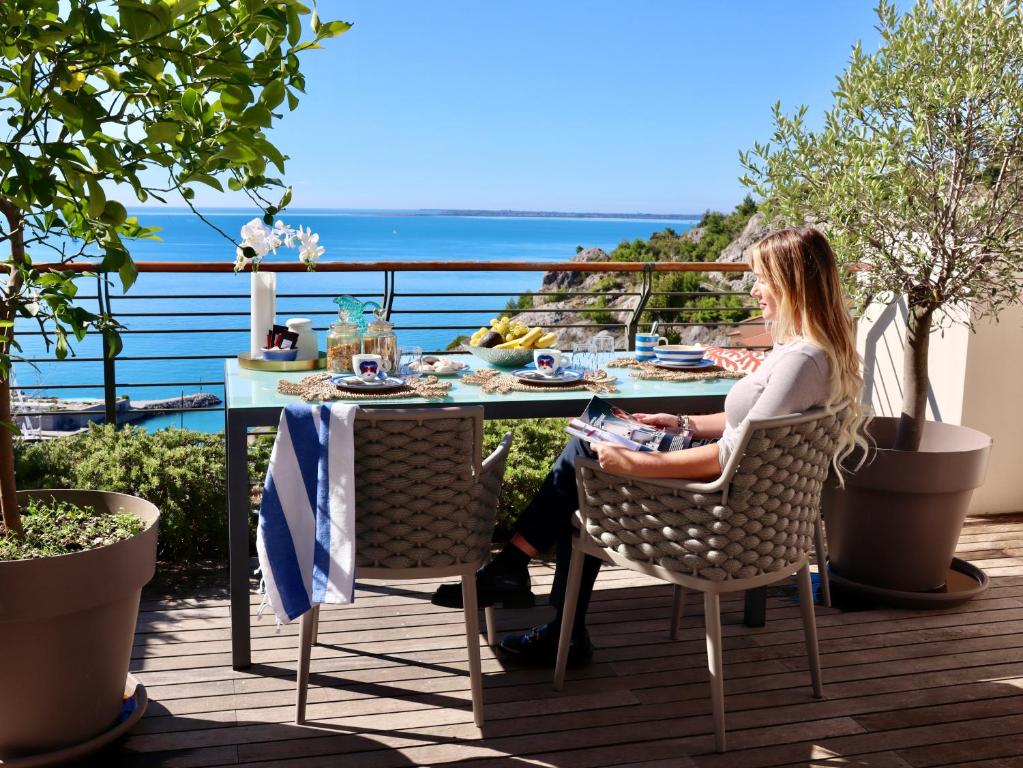 a woman sitting at a table on a balcony at Portopiccolo Apartments Deluxe in Sistiana