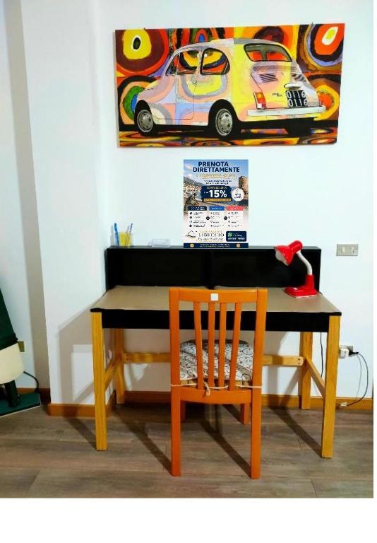 a desk with a chair and a painting on the wall at casa vacanze Libeccio parcheggio privato in Sapri