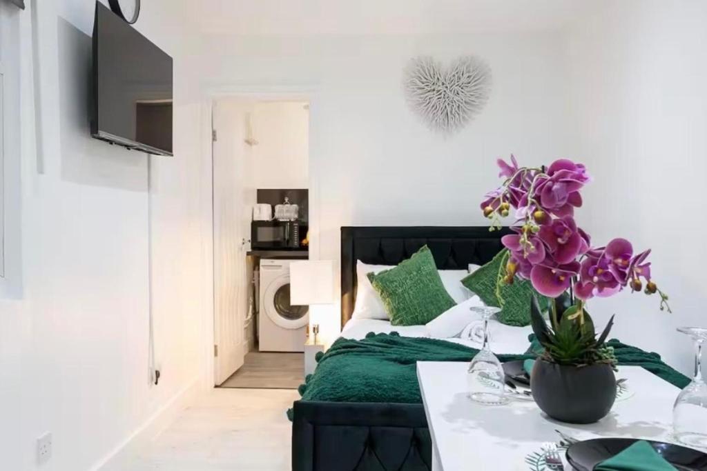 a living room with a bed and a table with flowers at Studio - Sleeps 2 - 5 Min to Trains - Parking in Thornton Heath