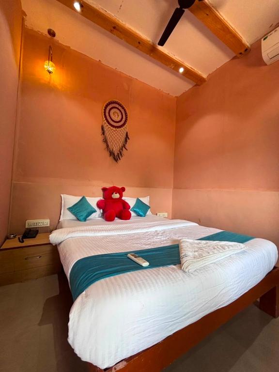 a red teddy bear sitting on a bed in a room at Roots in Pune