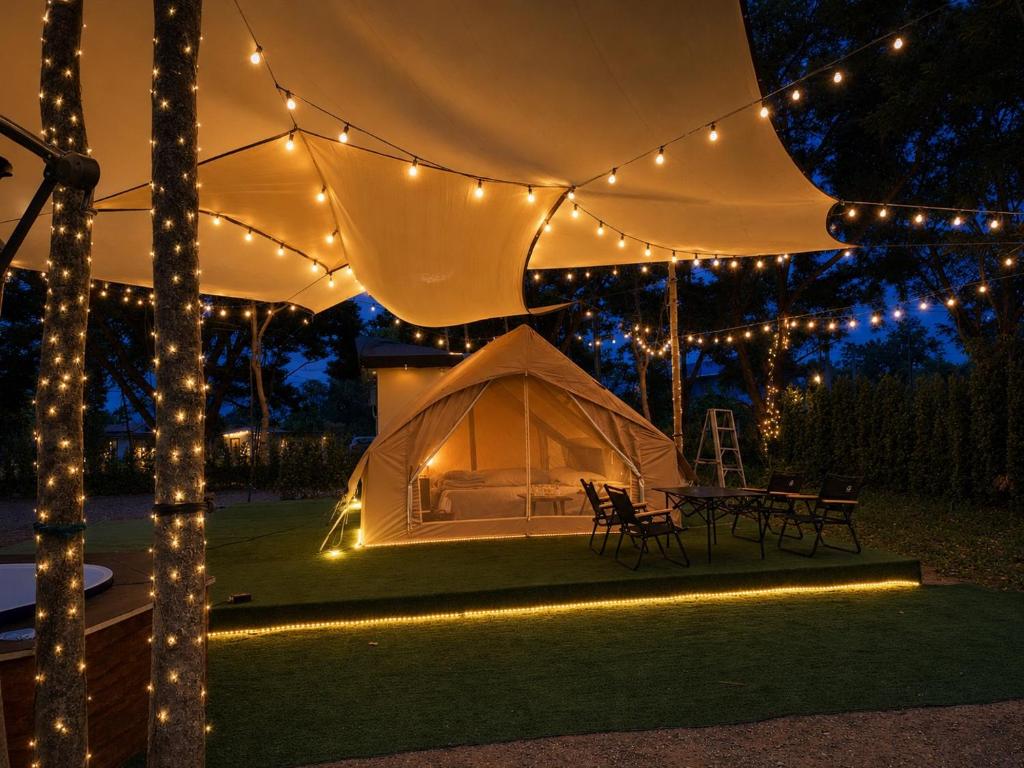 a tent and a table and chairs under lights at Riverside Glamping Resort Kanchanaburi in Kanchanaburi City
