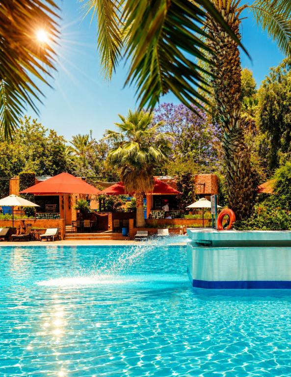 a pool at a resort with palm trees at Kennedy Hospitality Resort in Marrakesh