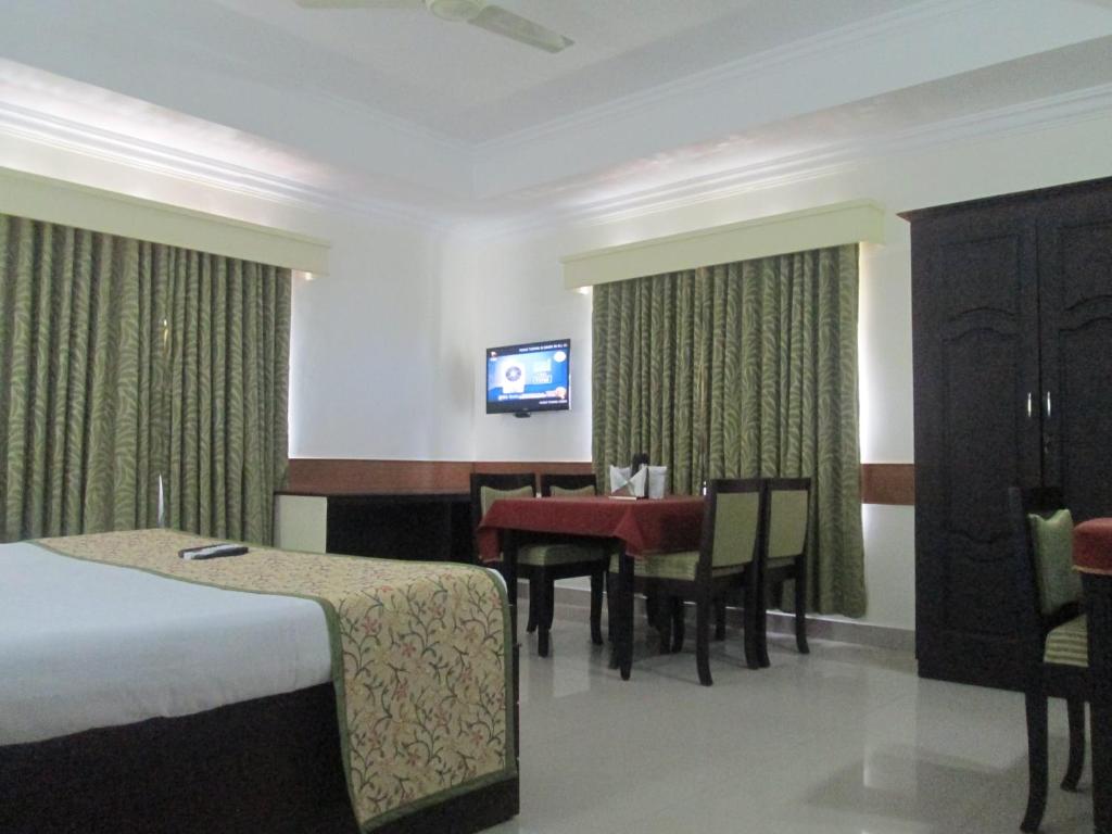 a hotel room with a bed and a table and a television at Paray Village County in Kollengode