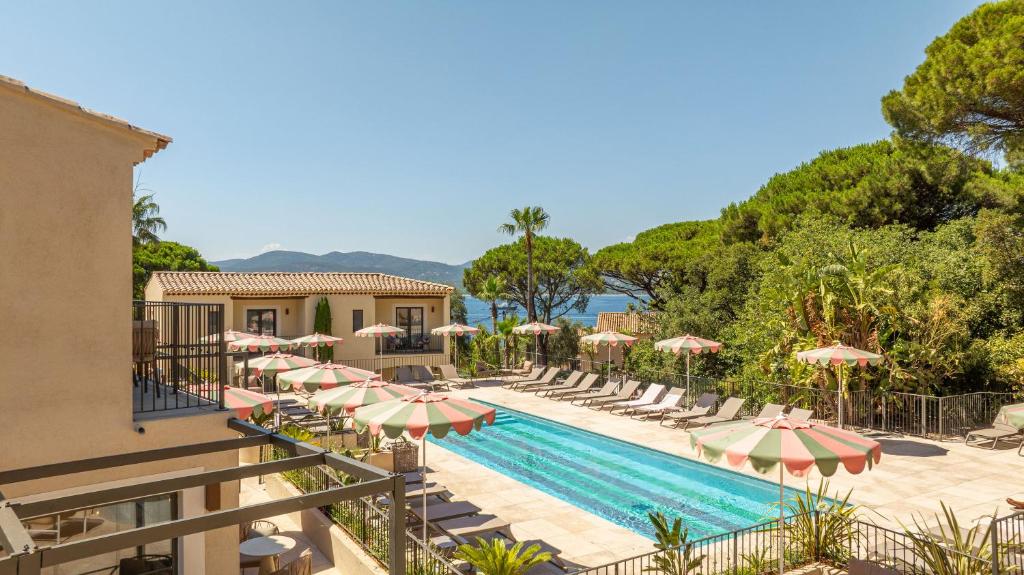 a resort with a swimming pool with umbrellas and chairs at Capucines Hotel Saint Tropez in Saint-Tropez