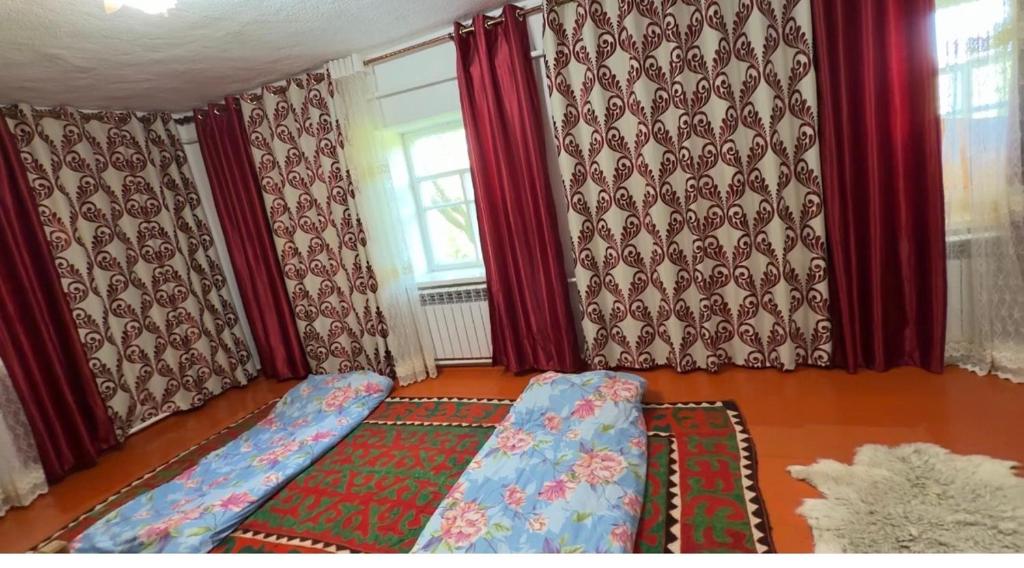 a bedroom with red curtains and a couch and a window at Felt painting in Kara-Suu