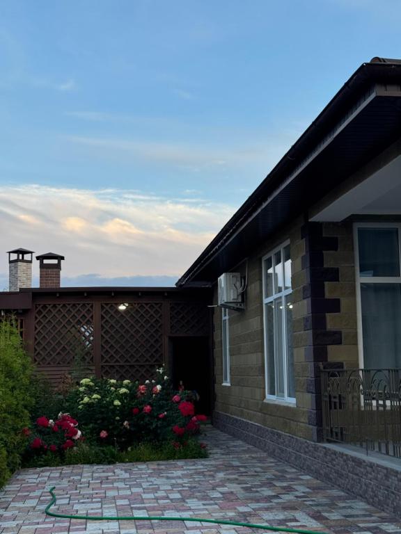a brick house with a patio and flowers in front at Cottage on Issyk-Kul, Royal Beach in Chok-Tal