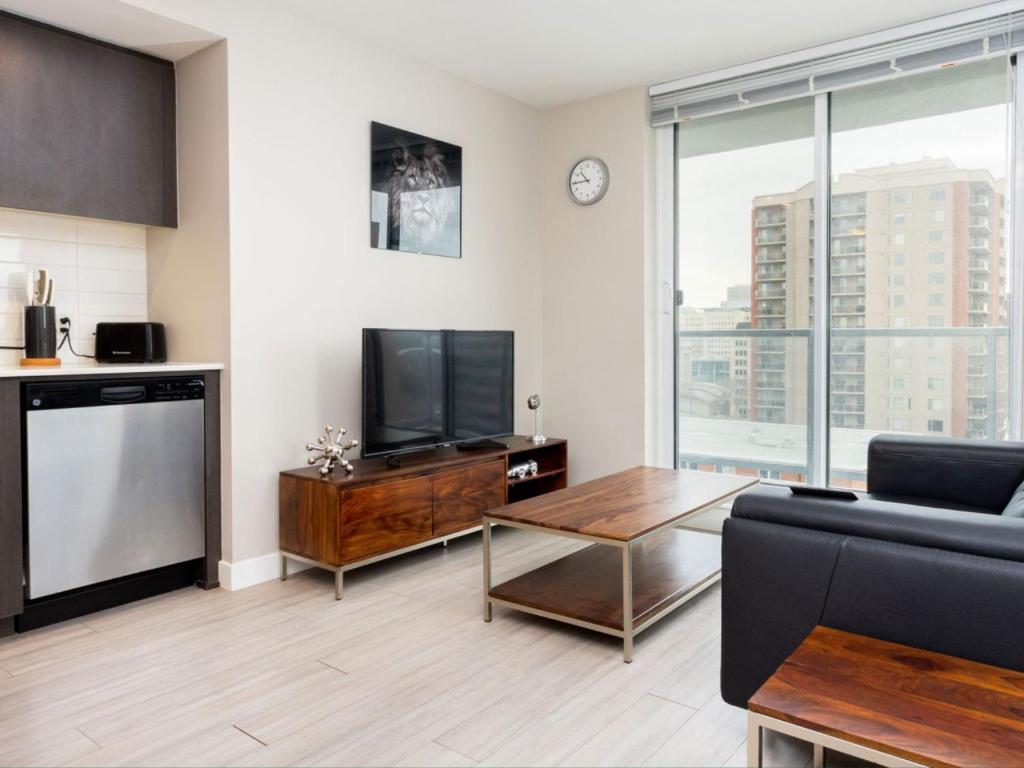 a living room with a tv and a couch and a table at Hendrix Luxury Apartments by Corporate Stays in Edmonton
