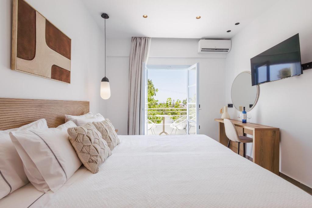 a bedroom with a bed and a desk and a television at Inoe Boutique Hotel in Kamari