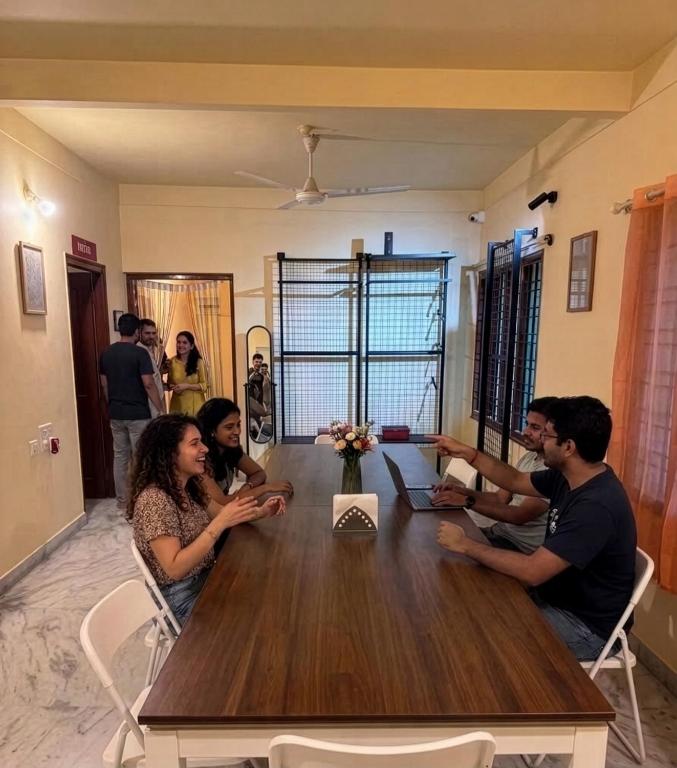 a group of people sitting around a wooden table at Pravaha Hostel in Bangalore