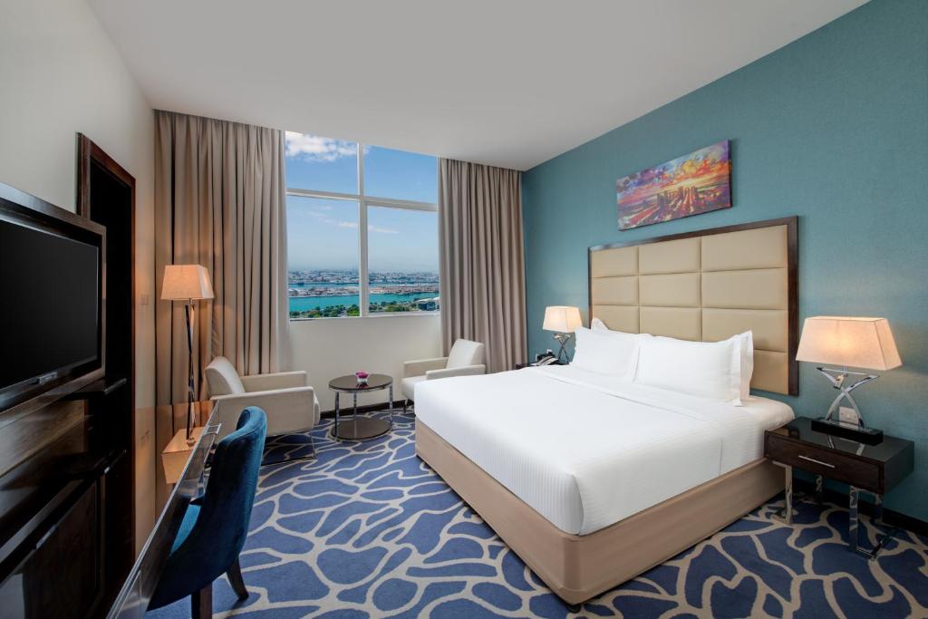 a hotel room with a bed and a flat screen tv at Ramada Abu Dhabi Corniche in Abu Dhabi