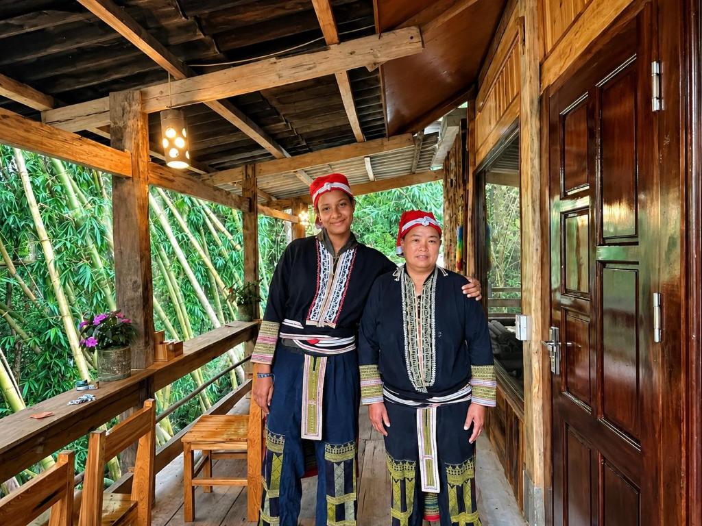 two people standing on the porch of a cabin at Red Dao Homestay and Entire bungalow in Tả Van