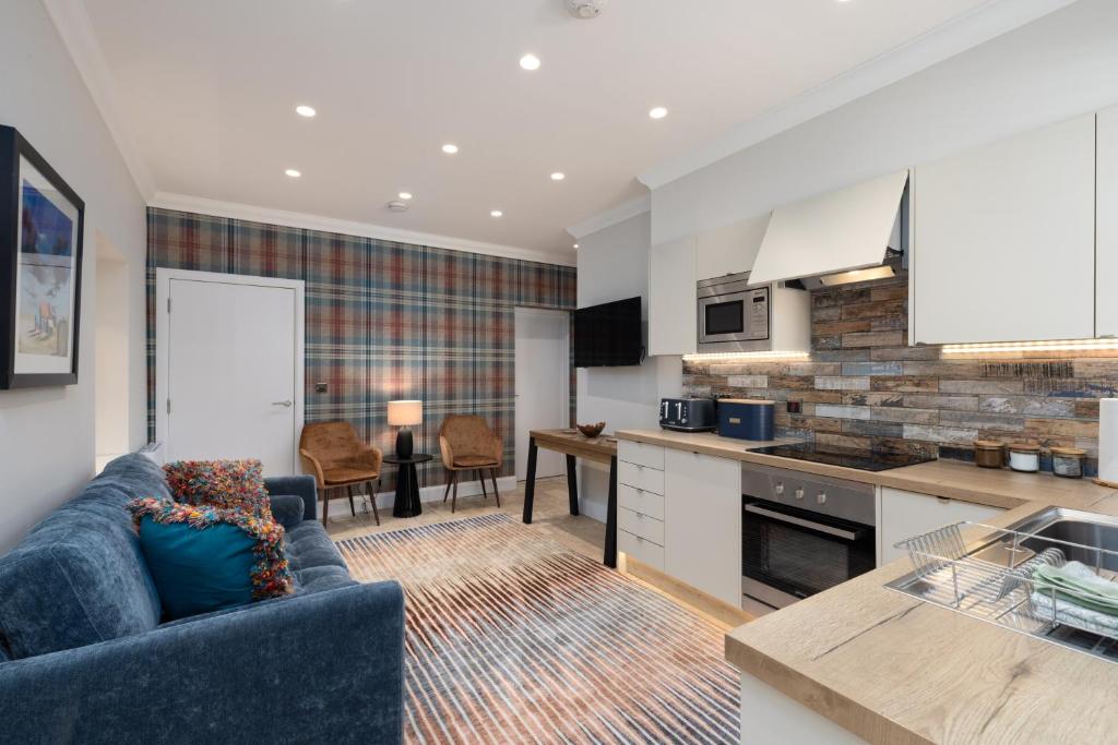 a living room with a blue couch and a kitchen at The Ford Apartment in Perth