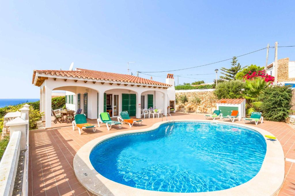 a villa with a swimming pool in front of a house at Villa Olga in Cala en Porter