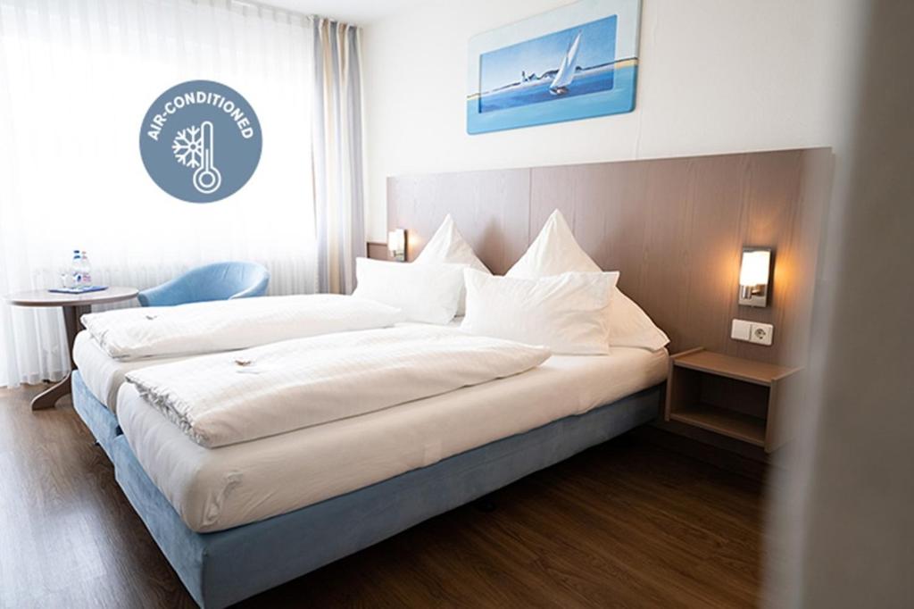 a bedroom with a large bed with white sheets at ates Hotel Kehl in Kehl am Rhein