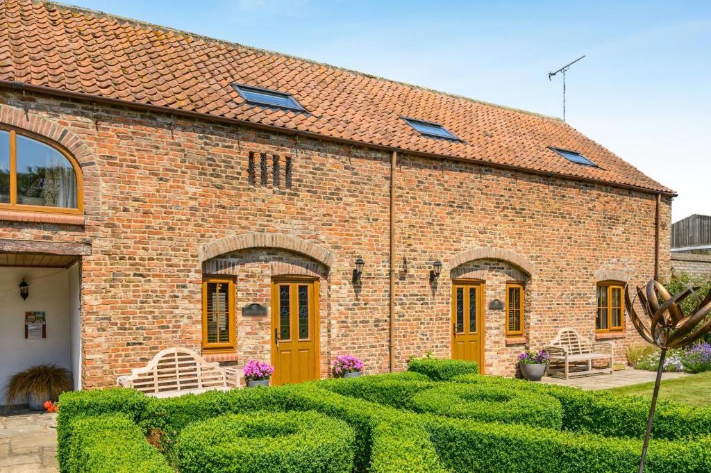 a brick house with yellow doors and a garden at 2 Bed in Driffield oc-79279 in Wold Newton