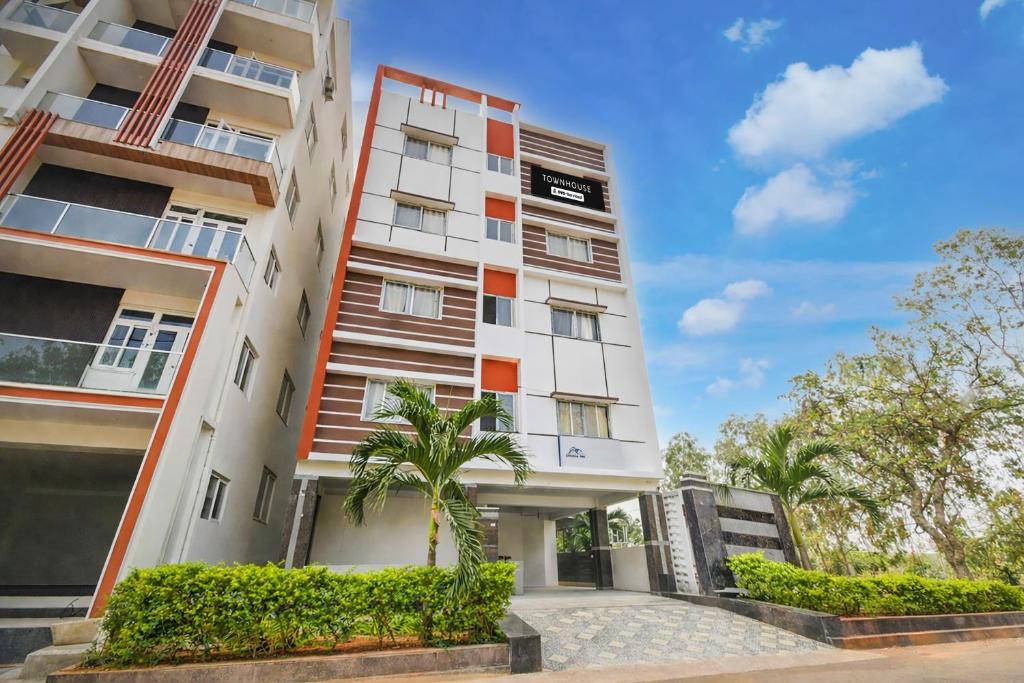 an apartment building with a palm tree in front of it at Super Townhouse Financial District Gachibowli Formerly Srinika Inn in Hyderabad
