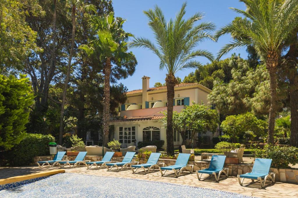 a group of lounge chairs in front of a house at MR Hotelet de la Raconà & Apartments in Denia
