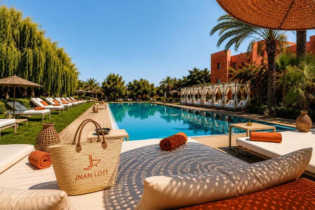 a pool at a resort with a table with a purse at Jnan Lotf Marrakech - Le Jardin de la Bienveillance in Marrakesh