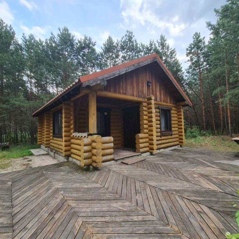 a log cabin with a deck in the woods at Log House Savin in Savin