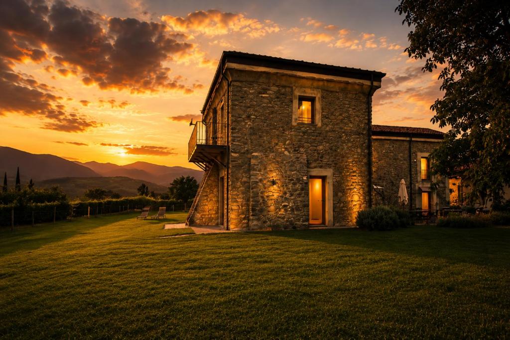 an old stone house with a sunset in the background at Podere Meroli in Scorcetoli