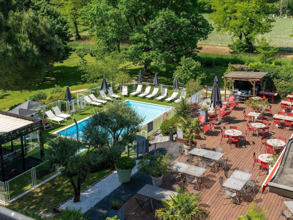 an overhead view of a pool with chairs and umbrellas at Novotel Grenoble Nord Voreppe in Voreppe