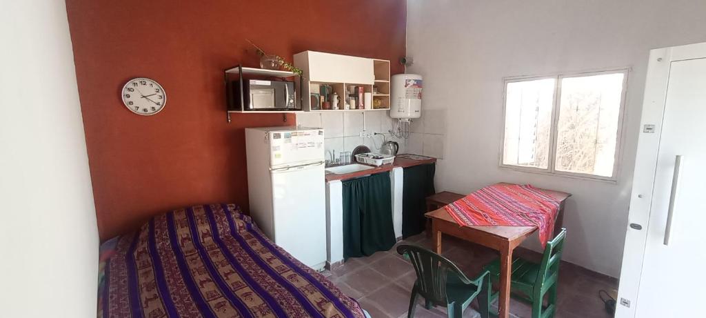 a kitchen with a white refrigerator and a table and a clock at Cabaña LDM cc in Santa Rosa