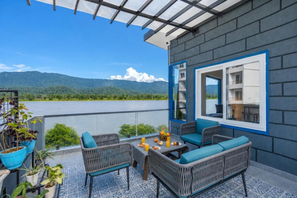 a patio with a view of the water and mountains at SaffronStays Tarangini by Ganges in Rishīkesh
