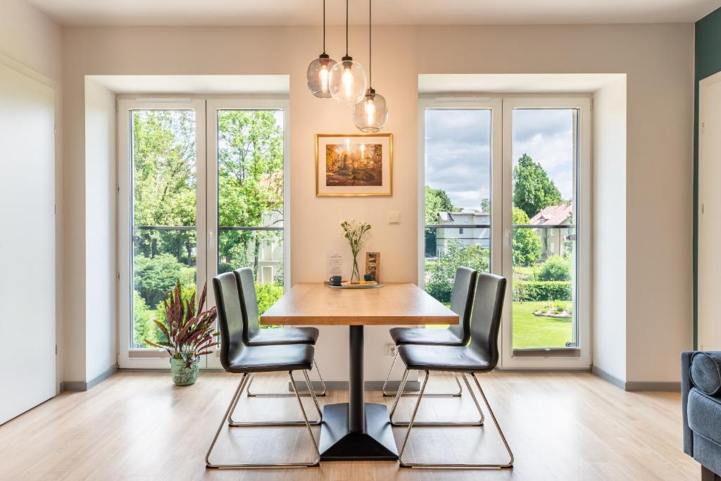 a dining room with a table and chairs in front of windows at APARTAMENTY ZDROJOWA 9 in Duszniki Zdrój