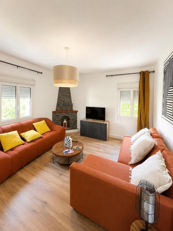 a living room with two orange couches and a fireplace at Maison moderne Parking &Jardin in Narbonne