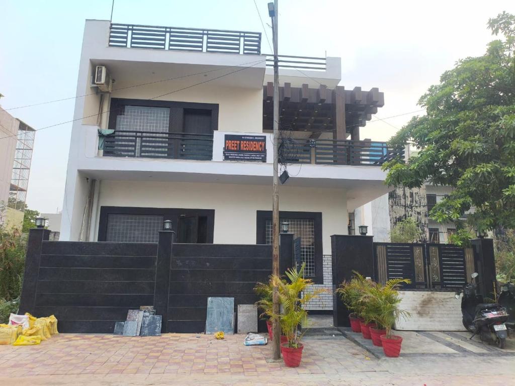 a white house with a balcony with plants in front of it at PLAY HOTEL PREET RESIDENCY couple friendly in Greater Noida