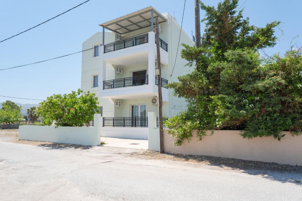 a white building with trees in front of it at Kos Happy living in Lampi