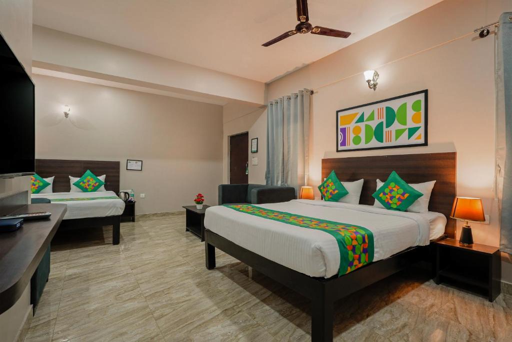 a hotel room with two beds and a television at Treebo Ksheera Residency Near Railway Station in Hassan
