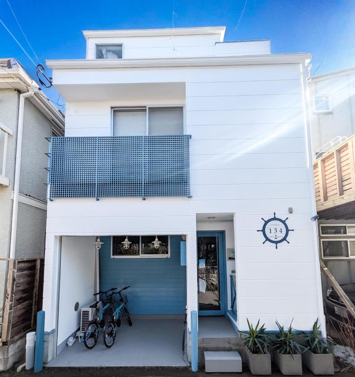 a white house with a blue door at Enoshima Guest House 134 in Fujisawa
