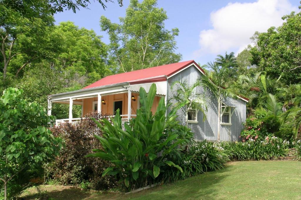 ein Haus mit rotem Dach im Garten in der Unterkunft Whitsunday Cane Cutters Cottage in Cannon Valley