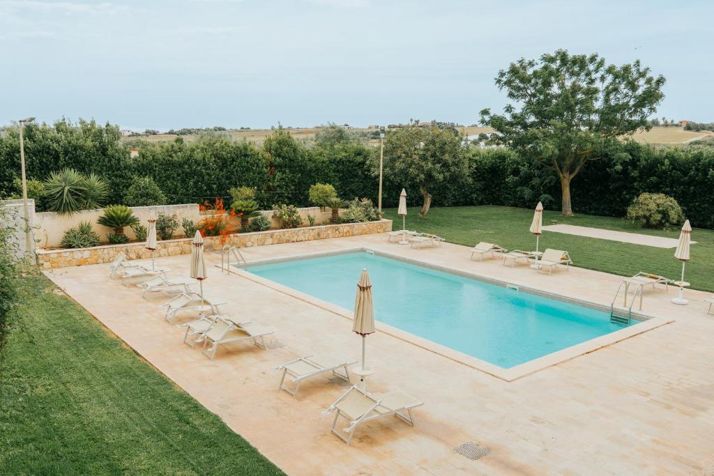 a pool with chairs and umbrellas in a yard at Dimora La Vignazza in Marzamemi