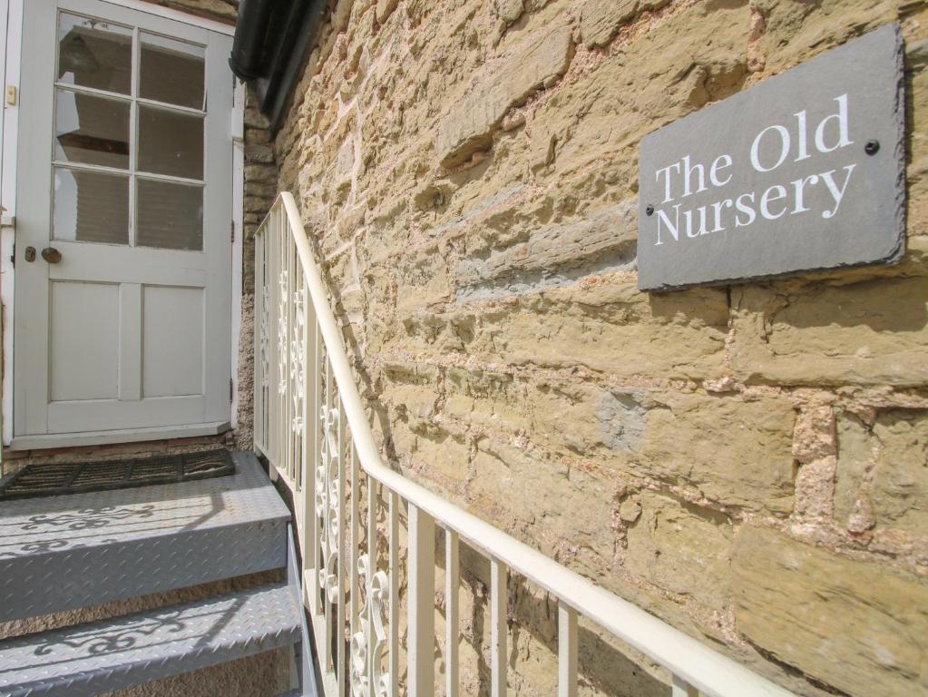 a sign on the side of a brick building with a door at The Old Nursery in Much Wenlock