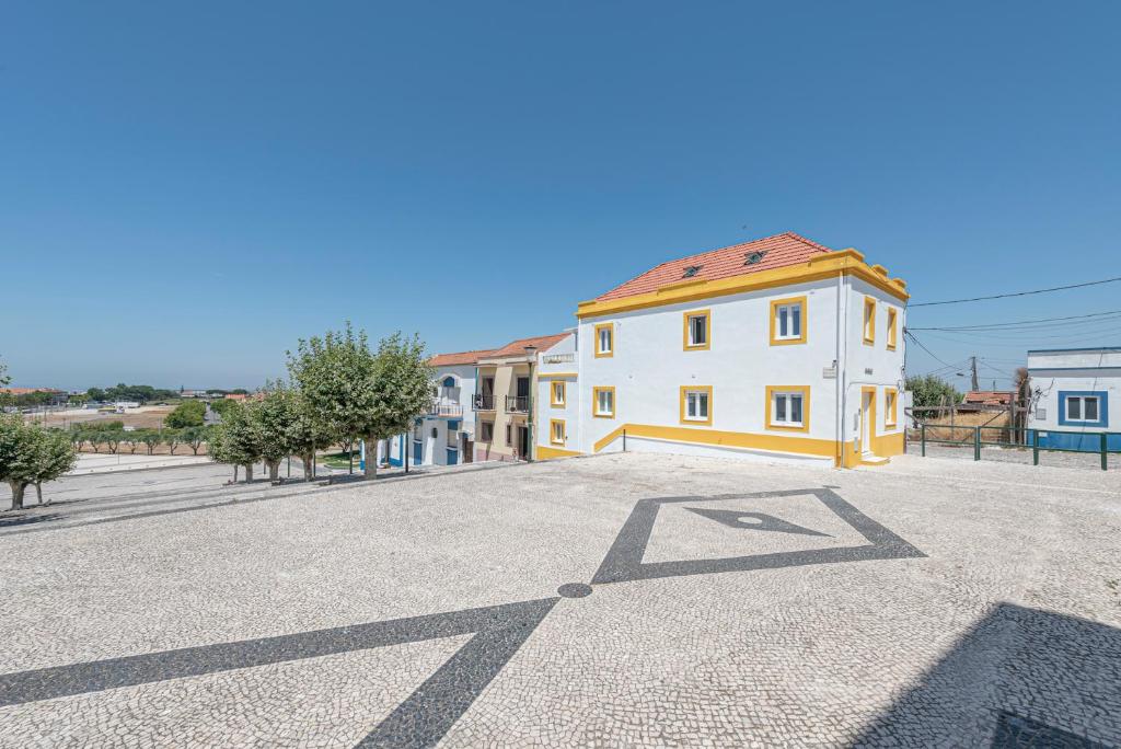 a large white building with a red roof on a street at Solar da Fé in Atalaia