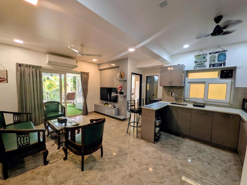 a kitchen and living room with a table and chairs at The Palm Retreat Luxe 1bhk Near Thivim Station in Advolpale