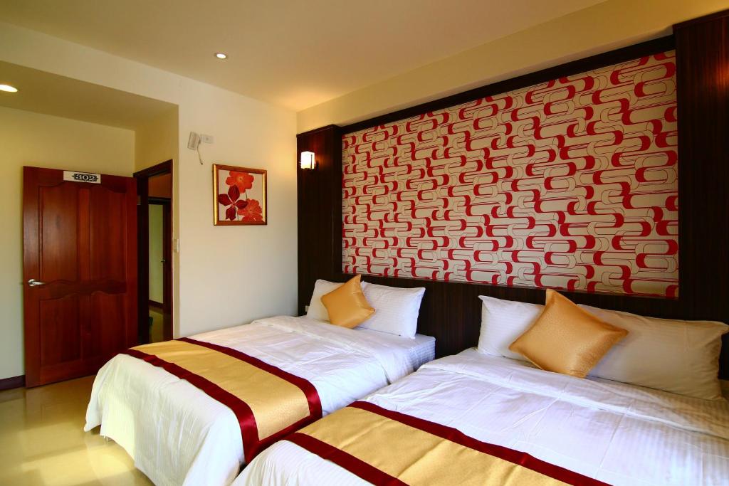 a bedroom with two beds and a red and white wall at Penghu Luna Sea Homestay in Magong