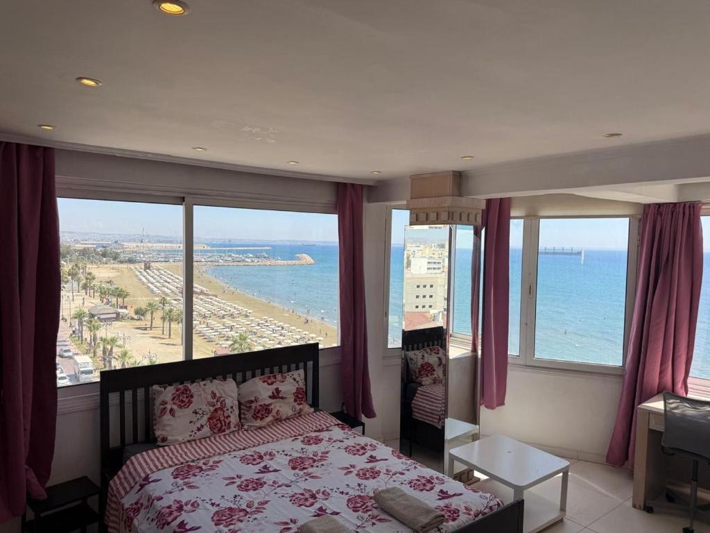 a bedroom with a bed and a view of the ocean at Larnaca Seaview Rooms in Larnaca