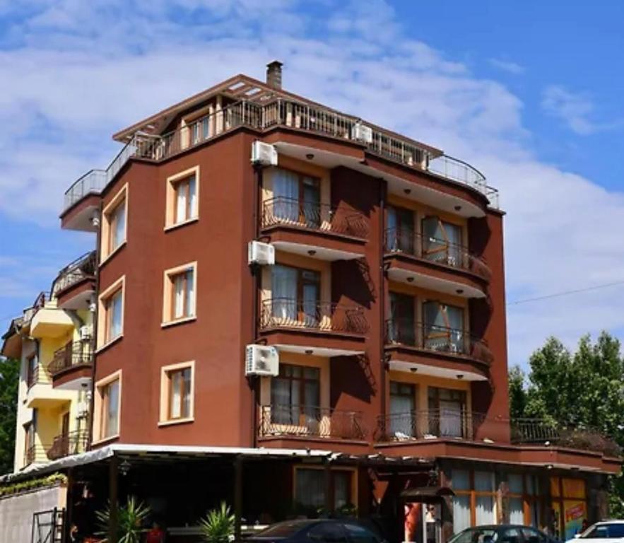 a red building with balconies and cars parked in front at Angel in Primorsko
