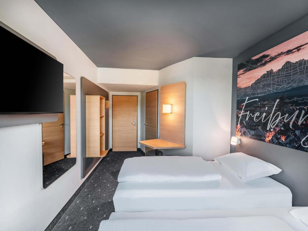 a bedroom with two beds and a painting on the wall at B&B Hotel Freiburg-Süd in Freiburg im Breisgau