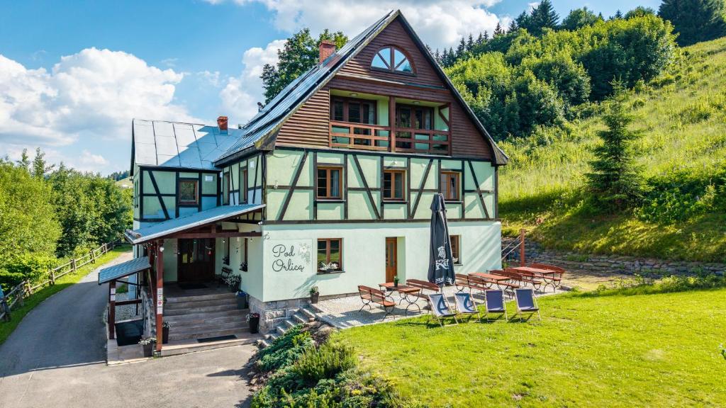 ein Haus mit einer Gruppe Stühle davor in der Unterkunft Pod Orlicą in Duszniki-Zdrój