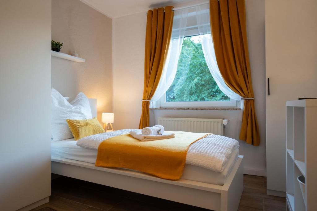 a bedroom with a bed with orange curtains and a window at Shaft by Loftigo - Apartment mit Wellnessdusche in Übach-Palenberg