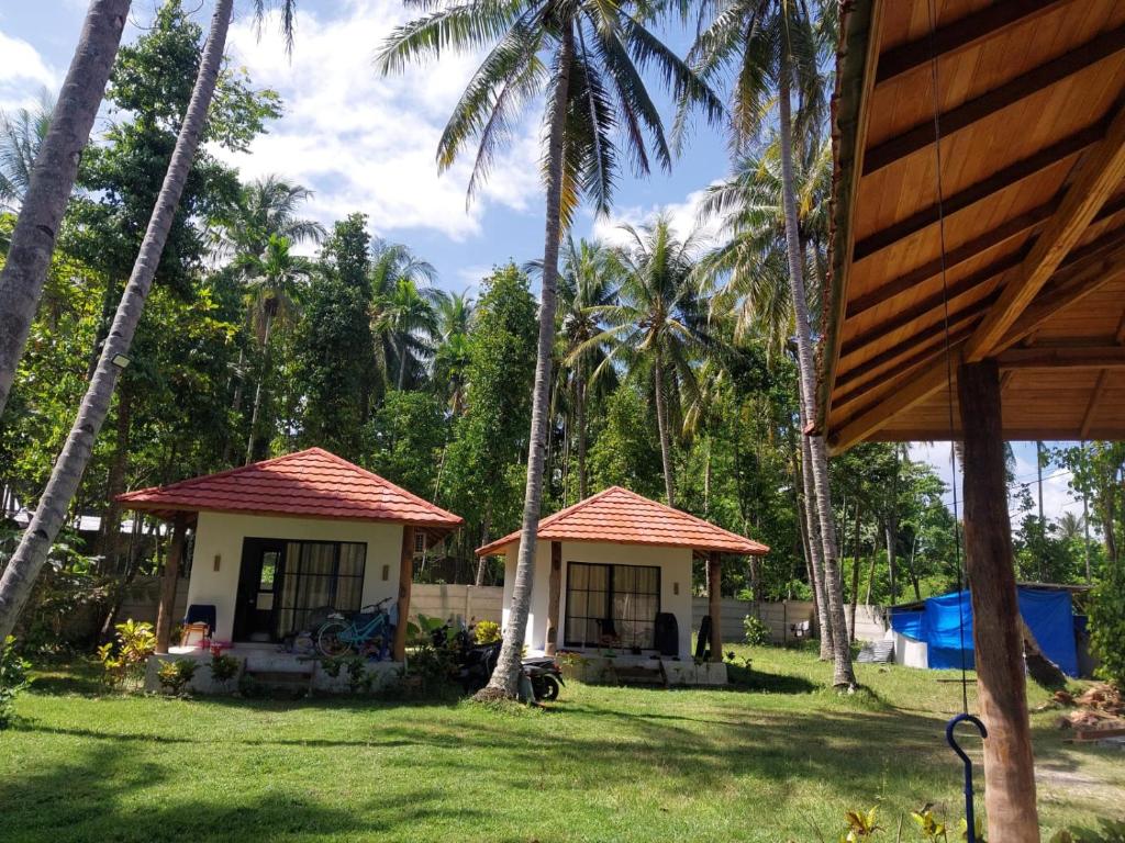 two small houses with palm trees in a yard at Slab Krui Bungalows in Krui