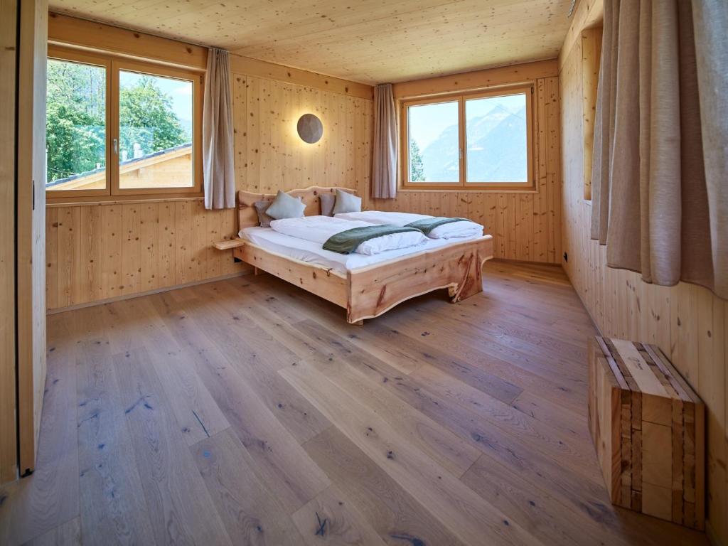 a bedroom with a bed in a room with windows at Holz100 Kleinhaus in Attinghausen