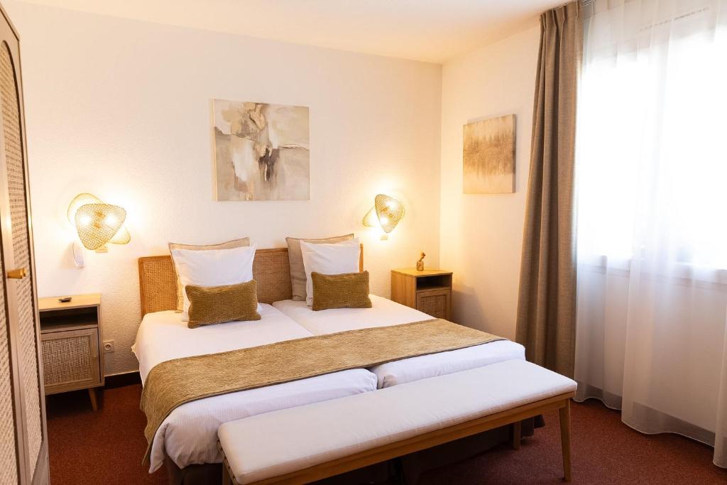 a hotel room with a bed with two pillows at Hôtel Deybach in Munster