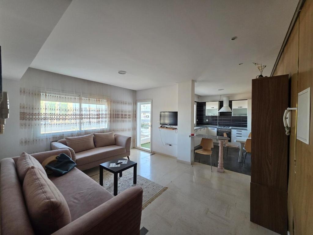 a large living room with a couch and a kitchen at luxurious two bedroom appartement in Hiboun