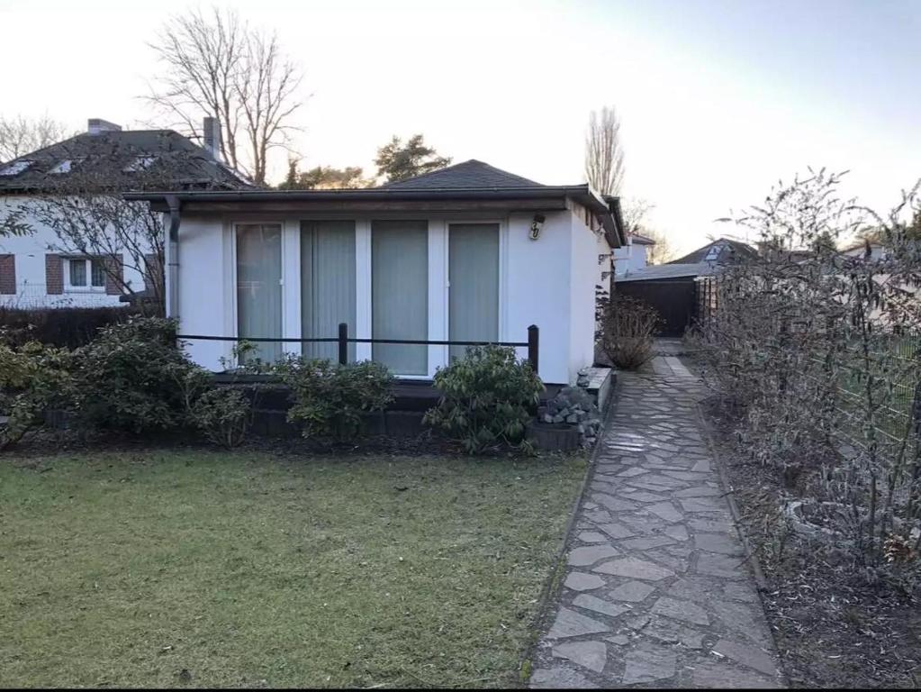 a white house with a walkway in front of a yard at Köpenick spree 1 bed room house in Berlin